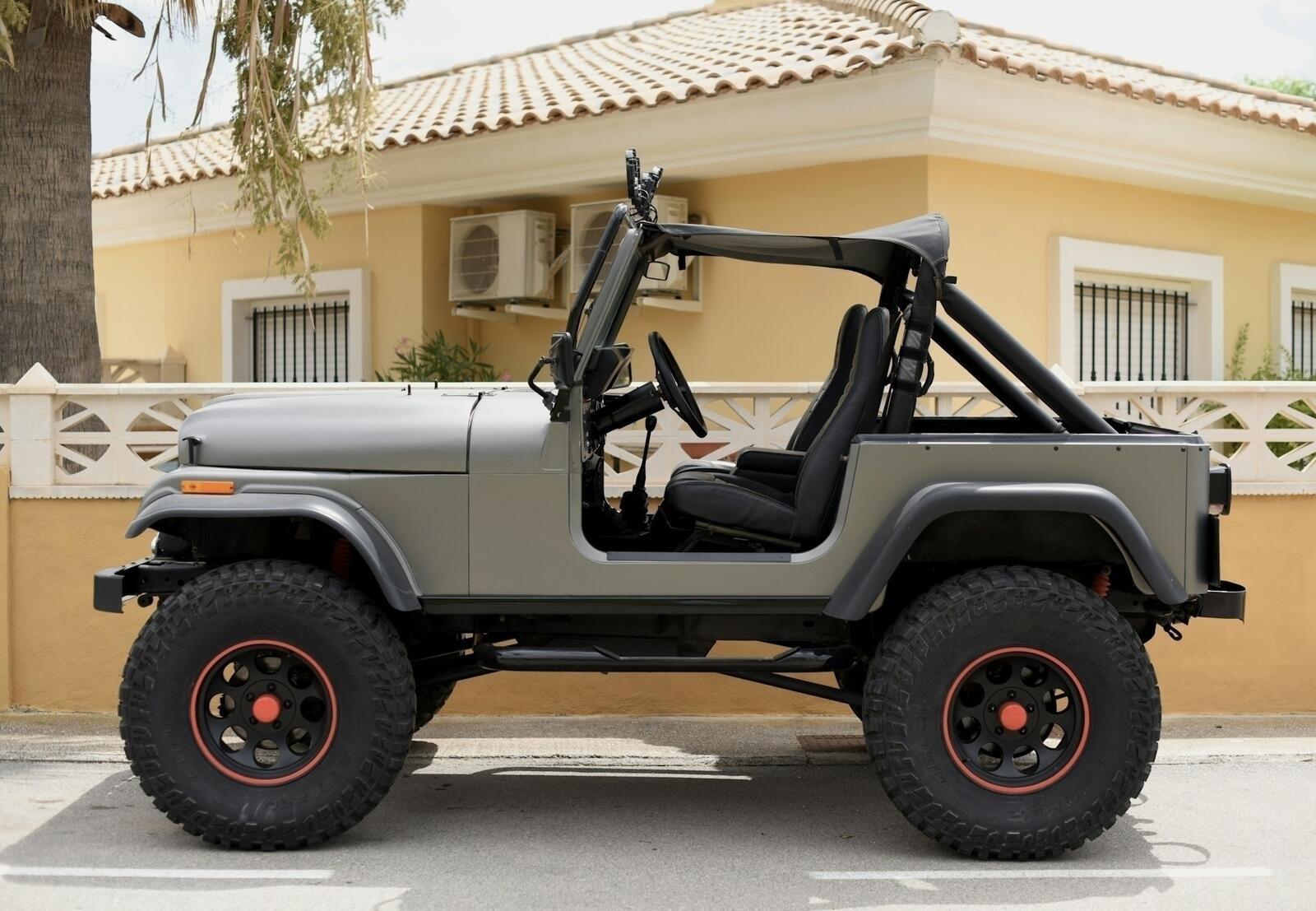 Jeep Wrangler with soft top removed, parked outside on a sunny day